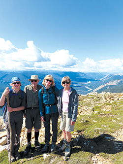 Four friends standing in front of blue skies with a canyon and river in the background